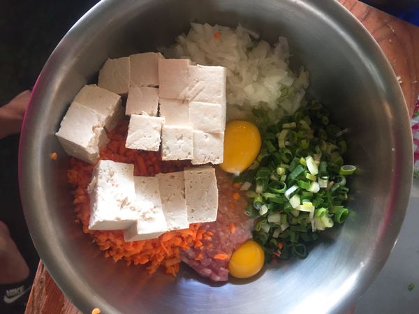 食材洗淨、青蔥切蔥花，洋蔥切碎，紅蘿蔔切碎，板豆腐切小塊（板豆腐請先靜置一會兒讓它把豆腐中的水跑出來）之後把所有食材放入盆中打入顆雞蛋攪拌。