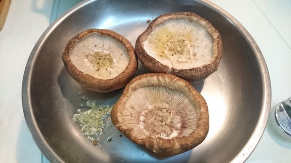 香菇清洗後稍微瀝乾後, 用紙巾將正反兩面按乾, 中間蒂頭剪掉, 可挖深一點才能容納多一點蛋, 香菇兩面灑上少許盬、胡椒粉, 並將正反面都塗上橄欖油
