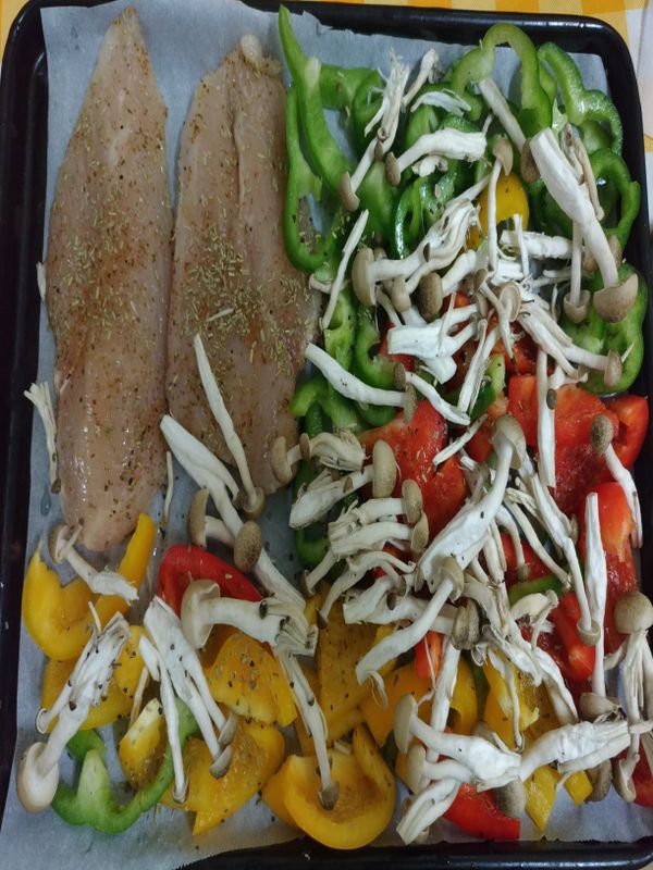 1.塗上少許油在烘焙紙上。
2.半副雞胸肉再切一半成薄片，灑上孜然粉,迷迭香。
3.鋪上彩椒青椒鴻禧菇，灑上調味料。如果怕口感太乾，還可以再塗些油在食材上，不塗也沒關係。