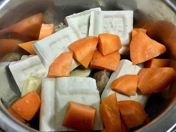 將食材放入悶煮鍋(肉塊、胡蘿蔔、豆乾、水煮蛋、蔥、滷包)