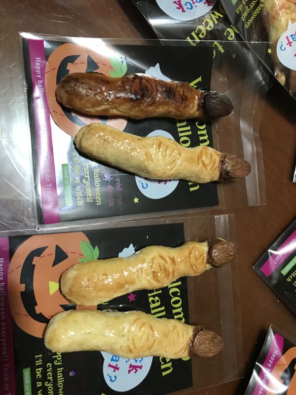 加熱熔化巧克力成巧克力醬；杏仁果沾取巧克力醬並黏貼於手指麵團條上。