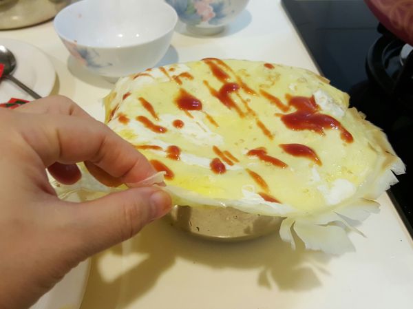 蛋皮放在碗公裡，將炒好的飯放進去，即可將飯包包起來，再用盤子倒扣即完成蛋包飯