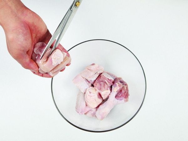 將雞肉塊裡的骨頭碎屑等雜質與內臟用清水洗淨去除後，用剪刀把雞肉剪成適當大小。