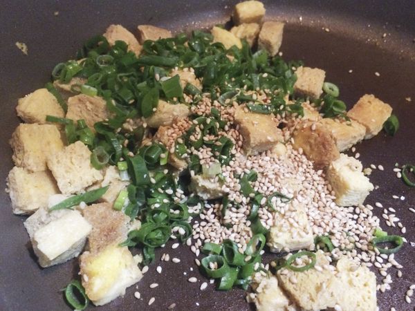 豆腐煎好後，加入米酒，醬油，味霖，蔥花，白芝麻，拌炒至乾爽，就可以上桌。