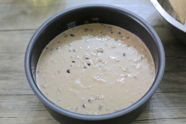將紅豆麵糊倒入電子內鍋中，桌面墊一塊布，在桌面震幾下震出氣泡，用矽膠抹刀整平。