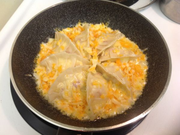 到約麵粉水已燒到剩約1/3,打開鍋蓋,在餃子間放入切達起司,再蓋上鍋蓋,將起司悶融化