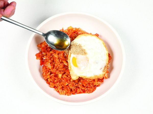 將炒好的泡菜炒飯盛盤，放上荷包蛋，再撒上芝麻鹽與香油¼ 大匙即可。