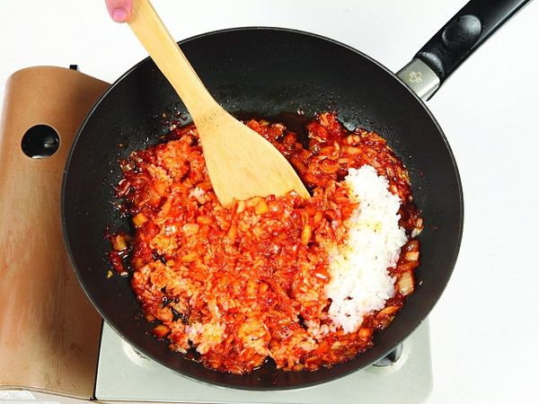 在關火的狀態下，倒入冷飯並與泡菜一起拌炒。