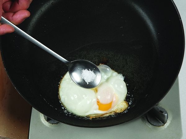 撒鹽在荷包蛋上，盛起置於盤中備用。