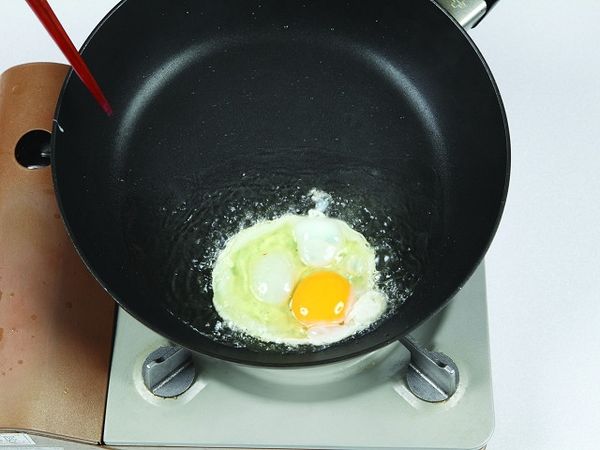 將食用油倒入寬口平底鍋，以大火熱鍋並把鍋子稍微往前傾，讓雞蛋在油鍋裡成半煎炸的狀態。
