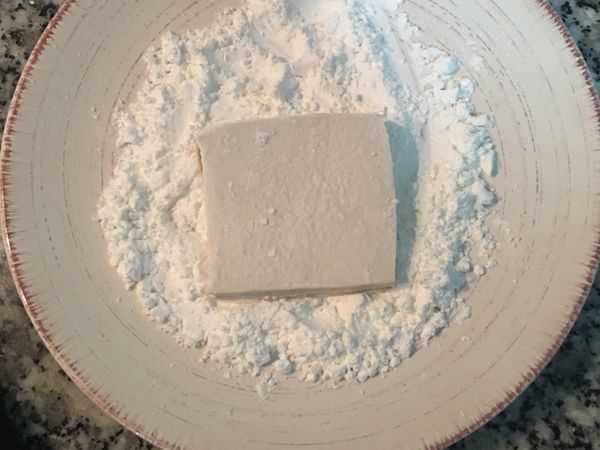 不沾鍋燒熱後放入適量的油，
將切片的豆腐兩面沾上薄薄的玉米粉。