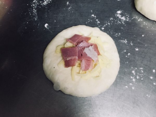 將麵團拍平，放置起司絲及培根，包起收口處黏緊，倒置