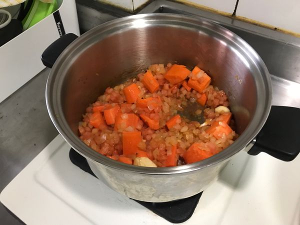 之後放入番茄醬，翻拌一下；加入紅蘿蔔與蒜頭，過炒一兩分鐘後，再加入蕃茄丁；停火靜置一下。