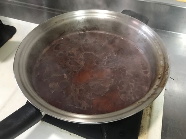 將淺鍋內多餘的油脂倒出，再稍微加熱後倒入紅酒，用木勺稍微刷鍋，將煎肉時鍋底的香煎物質刷下，同時蒸散酒氣。（Degrease &amp; Deglaze)