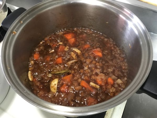 將淺鍋裡的紅酒倒入燉鍋裡加熱，加入一些調味料和月桂葉。