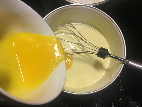 用另一碗將蛋黃攪散，滿滿倒進牛奶那一鍋裡，直到完全融合