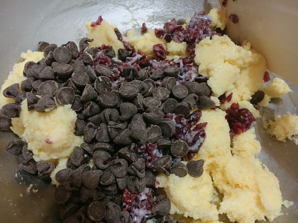 加入泡軟的蔓越莓與巧克力豆大致拌勻，加入已過篩的麵粉、杏仁粉與泡打粉。