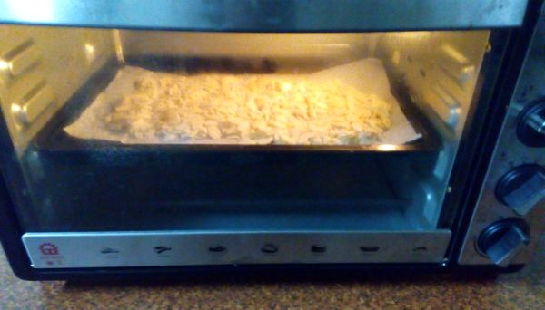 1包杏人片225g,我取一半包，約100g,放在舖滿烘培紙上烤箱130度烤10分鐘就好，取出。白芝麻事先有用炒鍋炒過。(晶工烤箱若遇熱很熱，所以用130度比較不容易黑。)