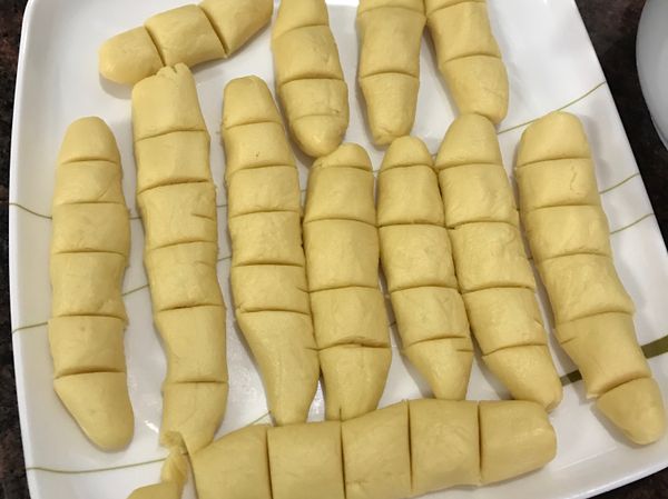 将面团揉成条状，再分至2cm一段。像包云吞一样放入适当的凤梨馅，包。做到一半这样，把烤箱预热15分钟，180度。