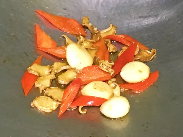 加入2大匙的麻油，將薑片煸至微捲曲後放入蒜仁爆香至略上色，再加入辣椒炒香。