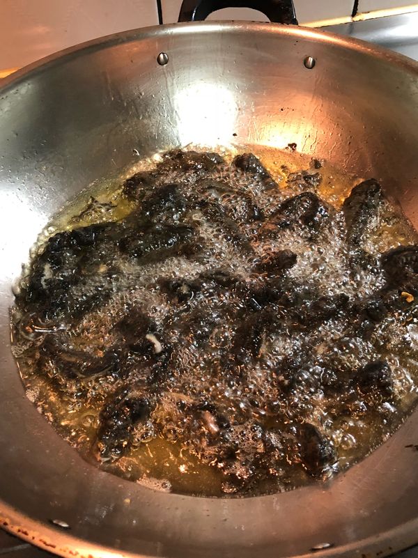 慢慢將裹好麵糊的墨魚放進去炸，剛放下的時候不要動，以免麵糊黏在到鍋底，稍等一下再動，就不會黏住了。