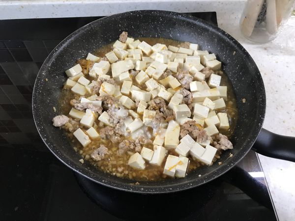 豬肉變色後放入豆腐、柳橙屑和糖、柳橙汁和剛剛混好的醬汁一起燉煮。