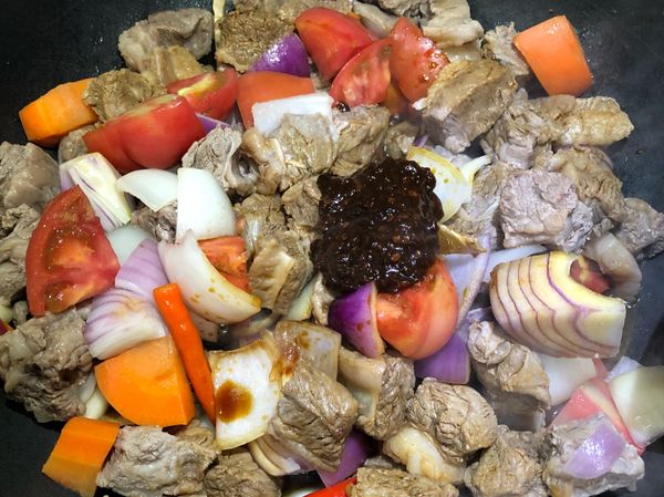 加入蕃茄、洋蔥、80cc的米酒、100cc的醬油、200cc的水、2～3匙豆瓣醬，拌炒至沸騰。