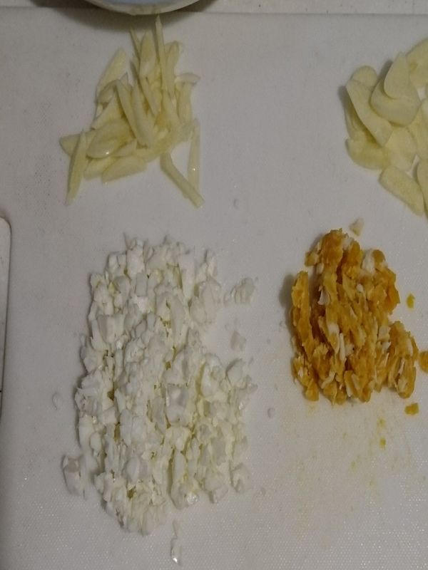 蒜頭切片再對半切，鹹鴨蛋蛋白蛋黃分開切，一般是只用蛋黃，剩下的蛋白可以料理其他菜肴或一同加入（此時可以先煮水）