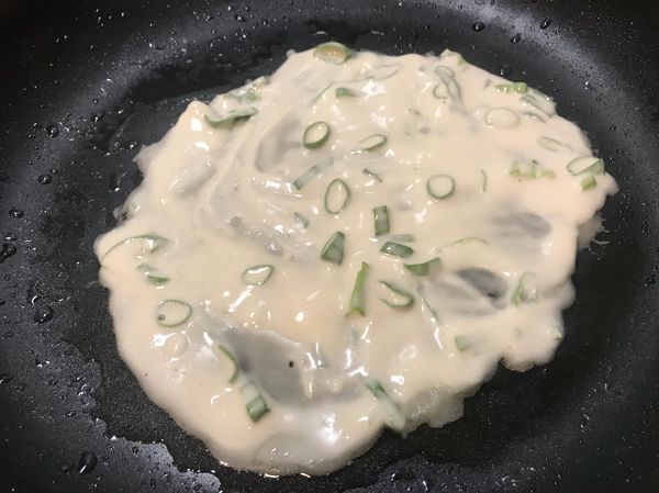 熱鍋後，加入少許油，待油溫微高時，熄火，
並倒入一杓匙的蛋餅麵糊，將麵糊弄成圓型。