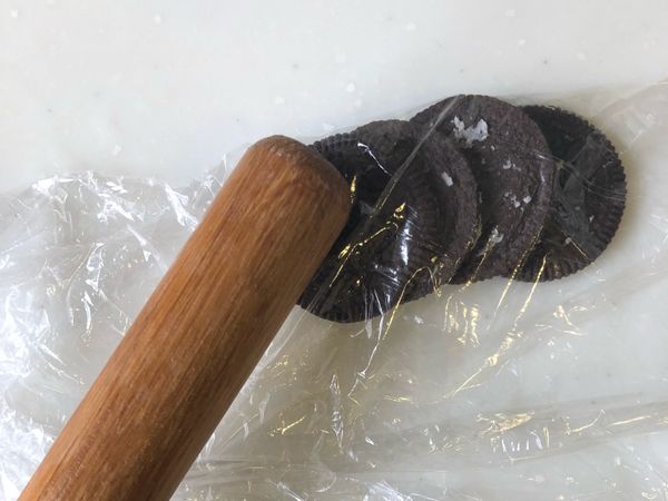 Oro餅乾去掉奶油 (大概是一包減三塊 其餘都要用哦）用保鮮膜包起來打碎 我用桿麵棍打碎的 我分兩次打