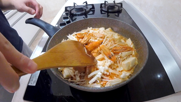 加入豆腐塊與切斷的金針菇。小火燉煮約3分鐘。
可使用市售的1/4海鮮湯塊調味，或是加入一般鹽巴調味。