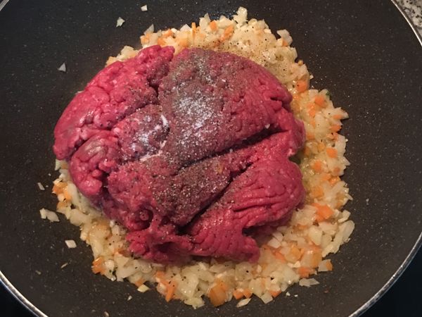 放入牛絞肉，並加入鹽、黑胡椒粉和紅椒粉；