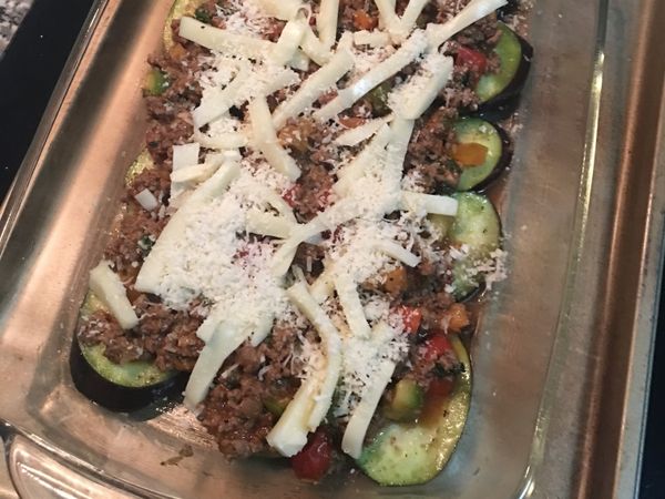 烤箱預熱到170度；準備好帶深度的烤盤，用廚房餐巾紙抹些橄欖油在烤盤上；先鋪一層茄子片和櫛瓜片，接著舀入牛肉餡，鋪滿在茄子和櫛瓜上；接著撒上馬薩瑞拉起司和帕馬森起司粉；