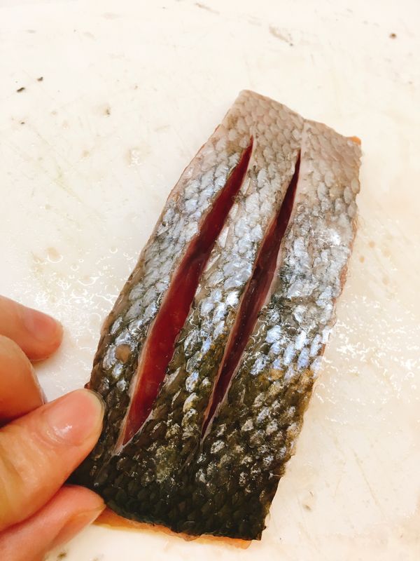 在鮭魚背面（皮）部分，用刀子劃下幾刀可以幫助鮭魚熟的比較快，更重要的是會讓皮更脆！