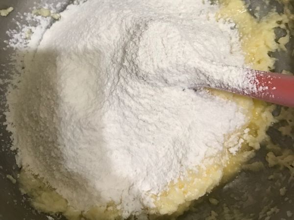 加入一大匙牛奶，再次過篩低筋麵粉和泡打粉到麵糊裡面用按壓的方式拌勻，不要過度攪拌