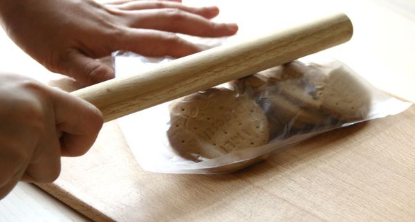 將消化餅乾放進塑膠袋裡，用擀麵棍敲碎，餅乾敲越碎越好，等等放入奶油比較好混和