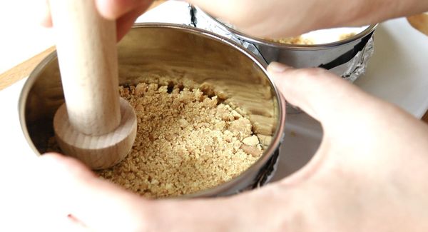 將餅乾碎與奶油拌勻後倒入蛋糕模中壓實