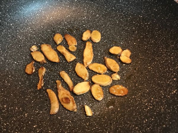 將切好的薑片與些許麻油倒入鍋中，用小火微微的乾煎，薑片被煸得差不多後再將剩下的麻油倒入繼續炒