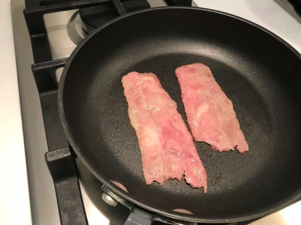 將培根放入熱鍋中，顏色稍微煎至亮紅熟化，即可起鍋，放置一旁將油拍乾，切碎。