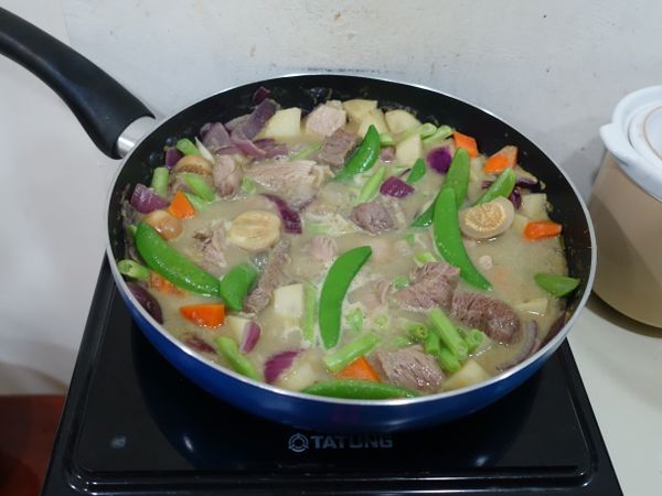 開鍋蓋，加入豬肉拌炒3-5分鐘，
再下越南茄子、洋蔥、四季豆、豌豆等易熟的菜，
加適量的水，蓋鍋蓋悶煮5-7分鐘，熟了之後就可食用。