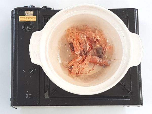 蝦子洗淨，去殻、去掉腸泥，蝦頭、蝦殼留用。
花蟹洗淨，掀起蓋子，去腮，去腹節。干貝浸泡至軟，然後撕成絲狀。墨魚切片，備用。
燒熱1茶匙油鍋，下蒜末炒香，加入蝦頭和殼炒約2分鐘。