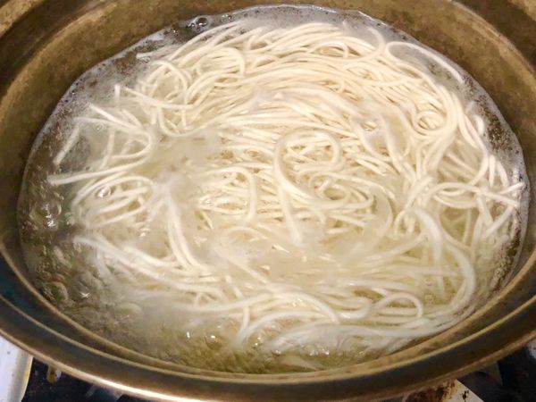 準備一鍋水煮沸，燒開後加入麵條及一杯水，一邊轉小火，一邊用筷子拌開，繼續煮滾約三分半鐘後撈起瀝乾。