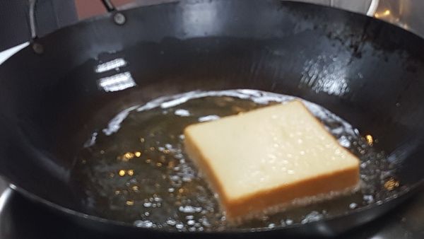 起油鍋, 厚土司用油炸, 因油炸要有一定的油溫( 不然吐司會回吸油很多) , 所以需用大筷子一直不斷翻動土司, 以免炸焦. (用烤箱烤酥也可)