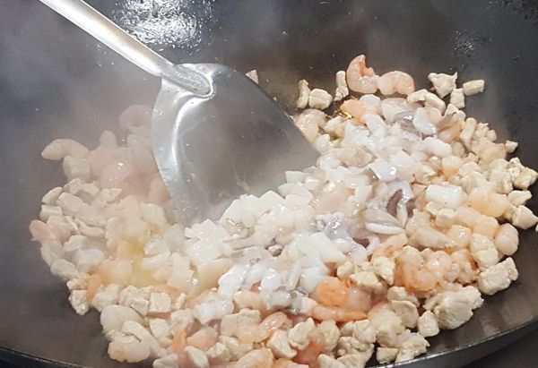 起鍋放奶油鮮放豬肉丁炒變色後, 放入川燙過的海鮮料,