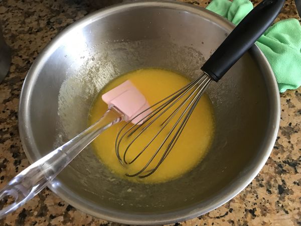 溶化的奶油移入盆中，加入蛋黃以及20g的糖粉拌勻。