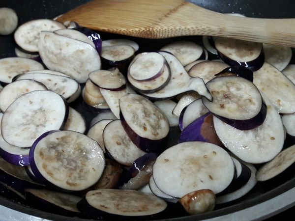 不沾鍋裡放油兩大匙，拌炒切成薄片的茄子。薄片快煮，但較為容易軟爛變形。
切成段厚實的茄子比較不容易變形，但是要熬煮較長的時間。依照自己喜歡的樣子切即可。