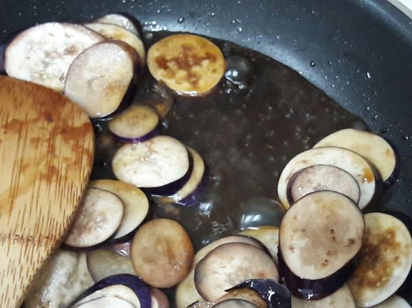 從熱鍋邊下醬油炒香一下。再加入米酒及烏醋及半杯水一起大火煮滾，煮到滾後轉中火燒煮2~3分鐘茄子煮軟。