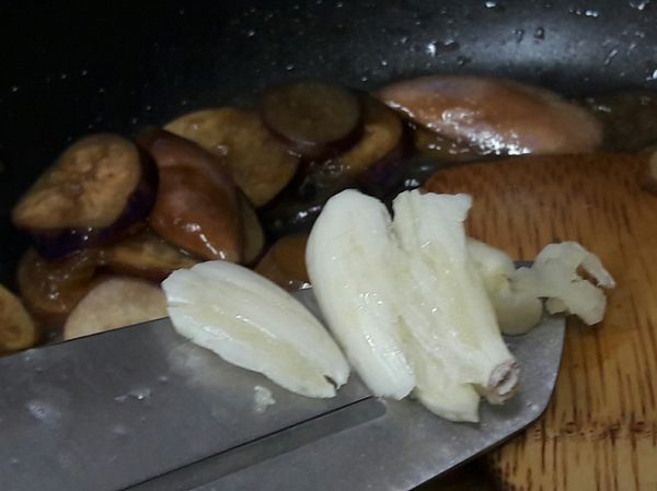 拌炒到茄子稍微軟化後，加入蒜末到鍋中拌炒一下。