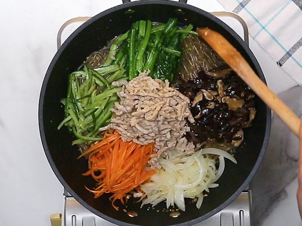 白芝麻下鍋煸香，放入醬油、糖、蒜末、麻油混合均勻，煮滾後熄火，倒入韓式冬粉，稍微拌炒均勻，倒入所有炒過的配料，拌勻即完成囉～