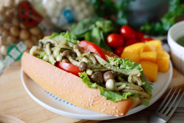 最後將長形麵包中間剖半，內面抹上菠菜青醬，擺上生菜、切片番茄與炒至入味的青醬菇菇，一道清爽的田園青醬菌菇堡就輕鬆完成囉！